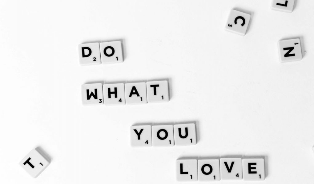 Scrabble tiles spelling 'Do What You Love' on a white background, encouraging creativity.