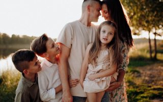 Family enjoying quality time together outdoors by the lake during sunset.