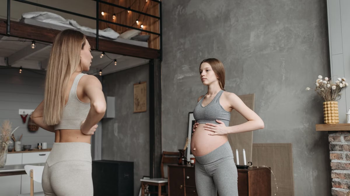 Expectant mother practicing prenatal yoga with guidance in a cozy home setting.